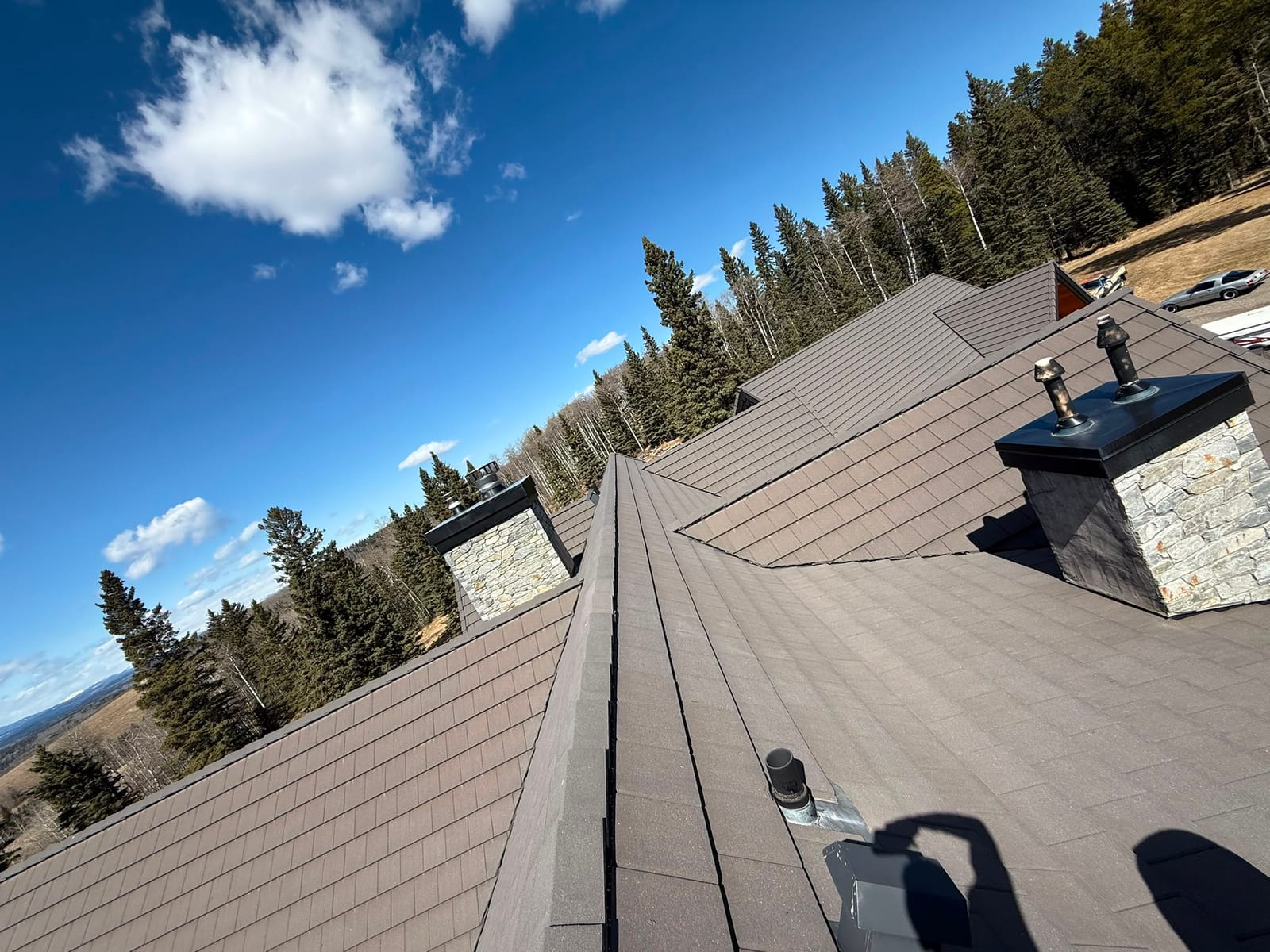 Shingle roof replacement completed on a Calgary acreage home with stone chimneys