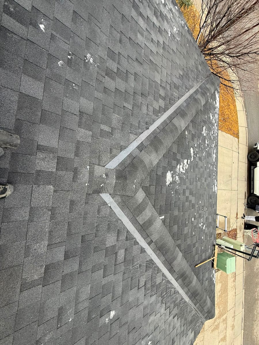 Aged asphalt shingle roof with worn closed valleys before replacement
