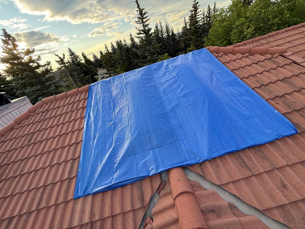 Emergency tarp secured over a damaged section of a Calgary tile roof